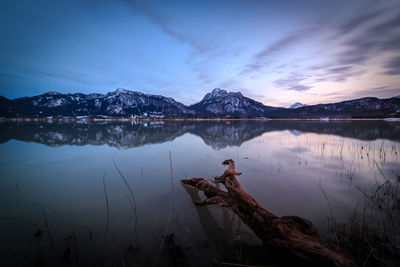 Scenic view of lake by snowcapped mountains against sky