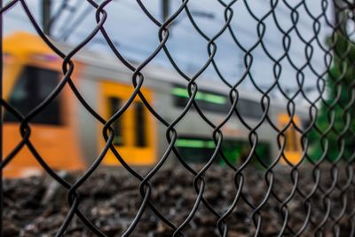 Close-up of chainlink fence with train in background