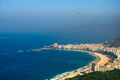 High angle view of city by sea against clear blue sky