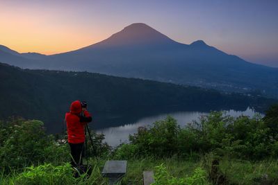 Rear view of man standing by mountains against sky