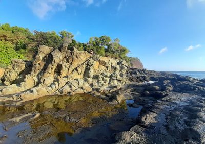 A rock wall behind a plateau from stones with water puddles at wediombo beach, java, indonesia