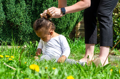 A mother wearing a smart watch ties a bow on her babys hair