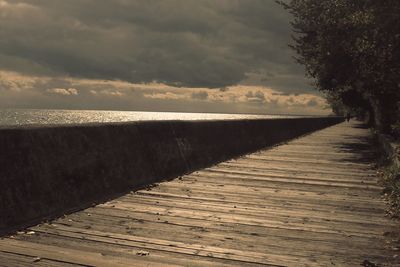 Narrow wooden pier leading to calm sea