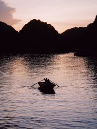 Silhouette boat in lake against sky during sunset