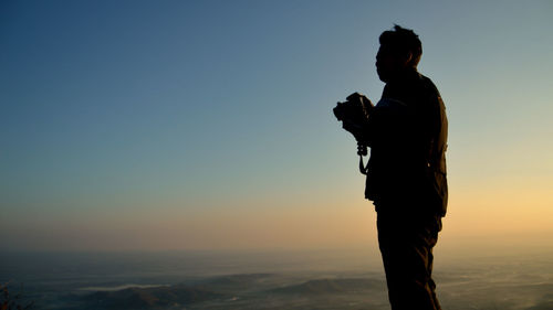 Silhouette man standing against sky during sunset