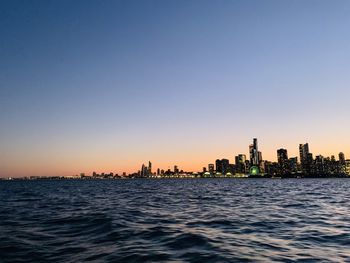 Scenic view of sea and buildings against clear sky