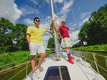 Two handsome young persons standing on a sailboat bow and looking at front, summer vacations