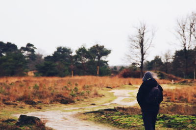 Rear view of man standing on field against sky