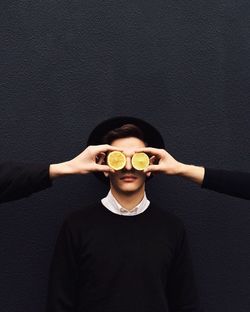 Cropped image of friends covering mans eye with lemon slices