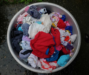 Colorful baby clothes for washing in an aluminum basin.