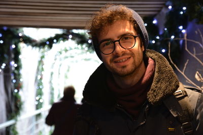 Portrait of young man against illuminated christmas decoration at night