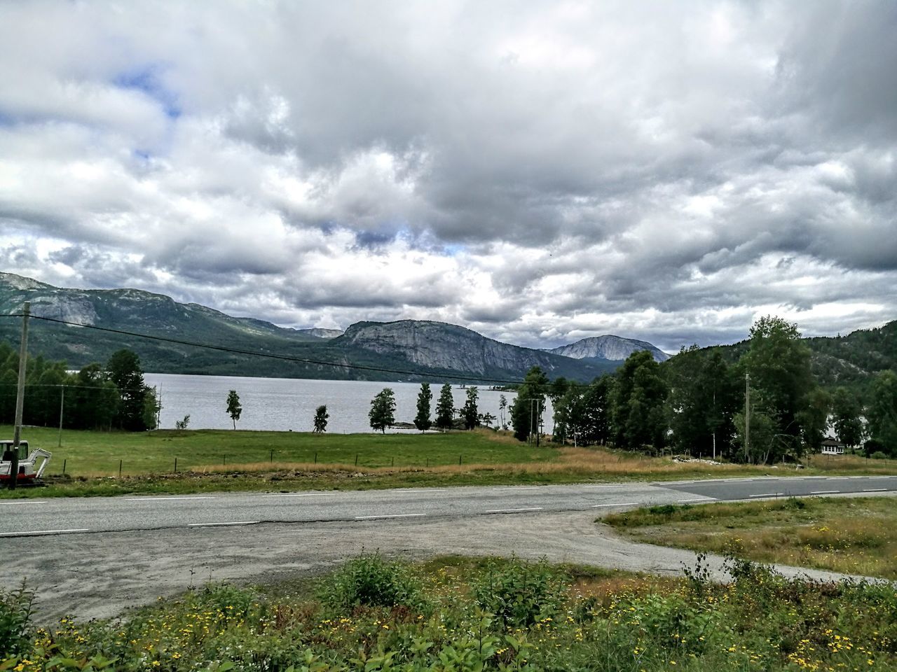 mountain, sky, cloud - sky, grass, cloudy, mountain range, tranquil scene, landscape, tranquility, scenics, cloud, beauty in nature, nature, tree, weather, grassy, non-urban scene, day, green color, idyllic, overcast, countryside, outdoors, remote, no people, growth, hill, non urban scene