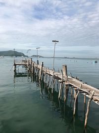 Wooden posts moored at harbor against sky