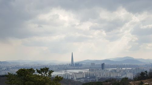 View of cityscape against cloudy sky