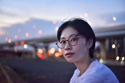 Portrait of woman against illuminated light at night