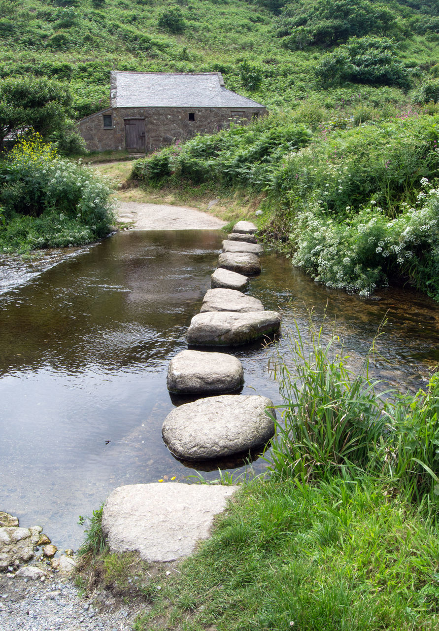 STONE WALL BY LAKE WITH PLANTS IN GARDEN