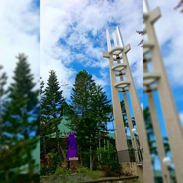 sky, low angle view, religion, cross, tree, spirituality, blue, day, cloud - sky, cloud, focus on foreground, built structure, outdoors, church, human representation, building exterior, architecture, place of worship