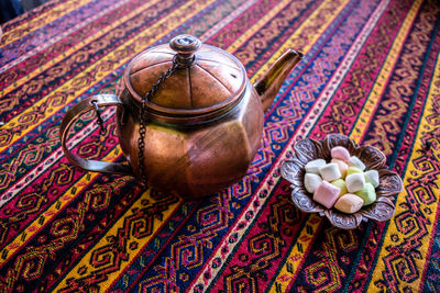 Close-up of tea kettle and candies in bowl on table