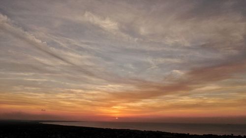 Scenic view of sea against dramatic sky during sunset