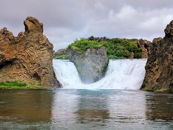 Scenic view of waterfall against sky