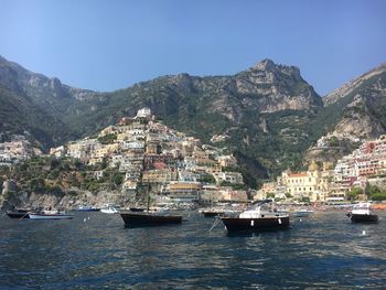 Boats in sea with buildings in background