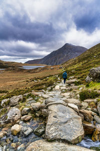 Rear view of person on rock against sky