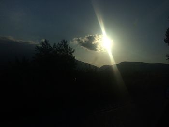 Sun shining through clouds over mountains