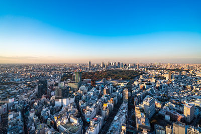 High angle view of city buildings against blue sky