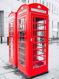 Red telephone booth on sidewalk in city