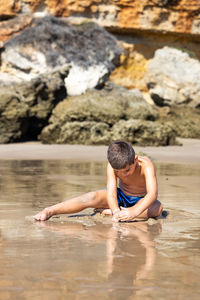 Little kid sitting on a rocky beach