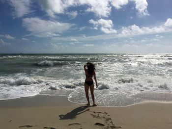 Woman walking at beach against sky