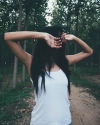 Rear view of young woman standing against trees