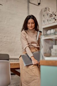 Smiling woman holding laptop at cafe