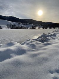 Scenic view of snow covered field against sky