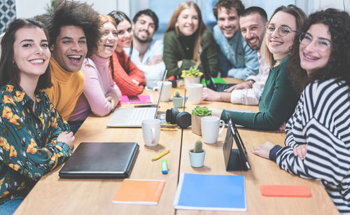 Portrait of cheerful coworkers sitting at table in office