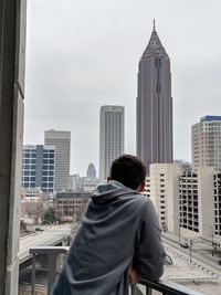 Man standing at balcony in city