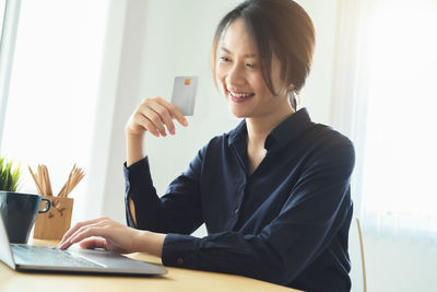 Young woman using phone while sitting on table
