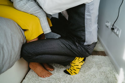 Low section of man sitting on bed