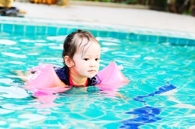 Cute girl with water wings swimming in pool