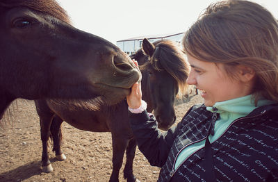 Young woman laughs feeling the velvet nose of icelandic horse connection with domestic animals, pets