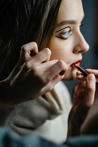 Cropped hands of make-up artist applying lipstick on female customer
