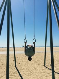 View of boy on swing hanging on beach