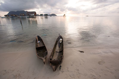 Boat moored on beach against sky