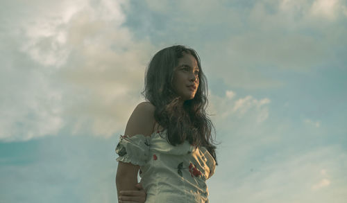 Young woman standing against sky