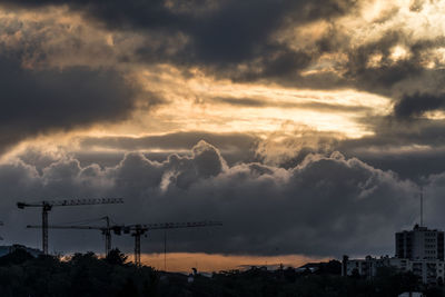 Silhouette cityscape against dramatic sky during sunset