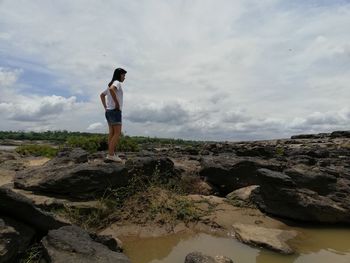 Full length of young woman standing on rock