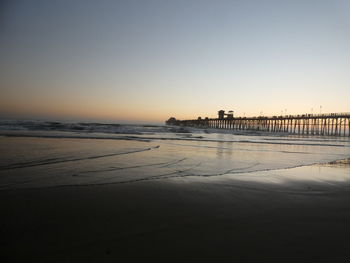 Scenic view of beach against clear sky during sunset