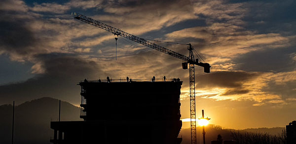 Low angle view of crane against sky during sunset