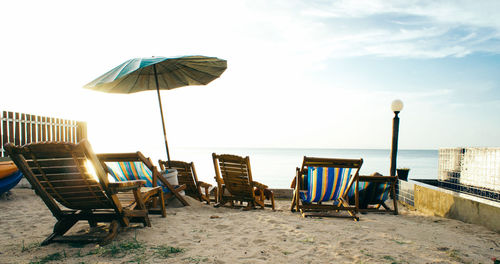 Deck chairs on beach against sky