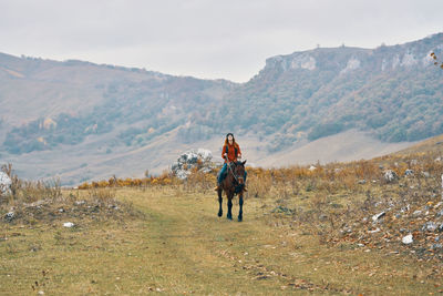 Rear view of friends standing on field against mountains